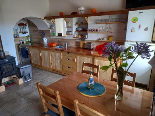 a kitchen with a wooden table with a vase of flowers on it at Casinha do Barreiro - Cosy Private Cottage in Vila do Porto