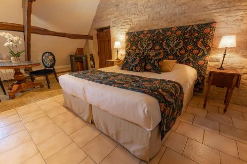 a bedroom with a bed and a table in a room at Ferme de la Rançonnière - Hôtel & Restaurant in Crépon