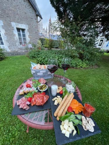 a picnic table with food and wine glasses on the grass at Villa des Roses in Pontmain