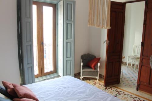 a bedroom with a bed and a window and a chair at Caserón Centenario in Cehegín
