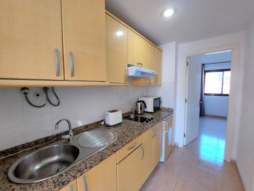 a kitchen with a sink and wooden cabinets at Sweet Home by Sea You There Fuerteventura in Corralejo
