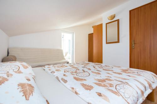 sypialnia z łóżkiem przykrytym kocem w obiekcie Apartmani Sandra Malinska w mieście Sveti Vid-Miholjice