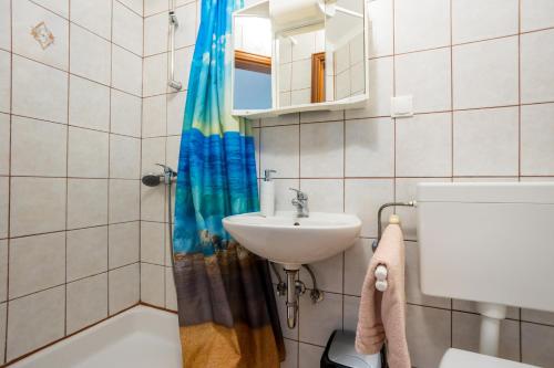 uma casa de banho com um lavatório e uma cortina de chuveiro em Apartmani Sandra Malinska em Sveti Vid-Miholjice