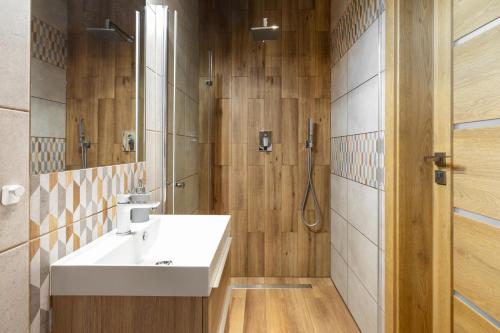La salle de bains est pourvue d'un lavabo et d'une douche. dans l'établissement DOMKI TU I TERAZ, à Szczawnica
