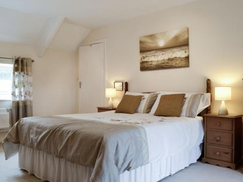 a bedroom with a large white bed with two lamps at Middleton Hall in Rhossili