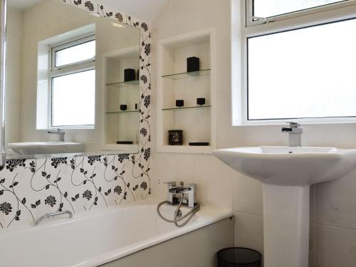 uma casa de banho branca com um lavatório e um espelho em Middleton Hall em Rhossili