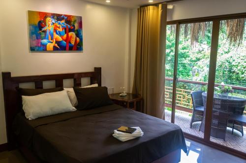 a bedroom with a bed and a sliding glass door at GIARDINO ROMANTICO in Dumaguete