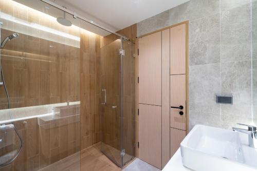 a bathroom with a shower and a sink and a glass door at By The Beach Home in Patong in Patong Beach