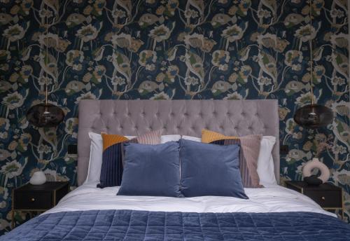 a bedroom with a bed with blue sheets and floral wallpaper at Honeysuckle Lodge in Knaresborough