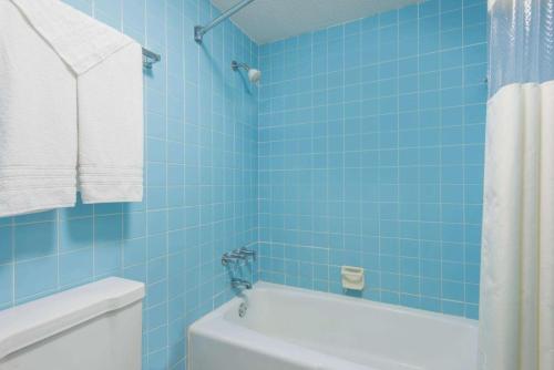 uma casa de banho com azulejos azuis, uma banheira e um WC. em Haven Inn & Suites St Louis Hazelwood - Airport North em Hazelwood