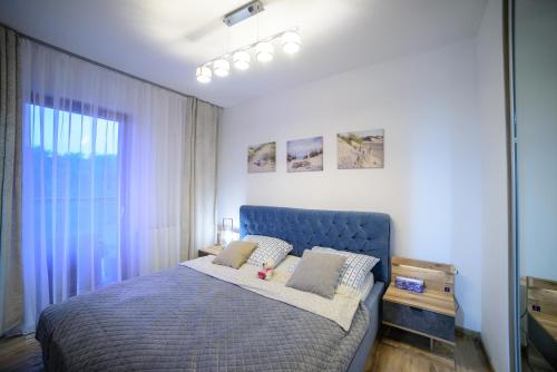 a bedroom with a blue bed and a window at Apartamenty Via Marina in Wrocław