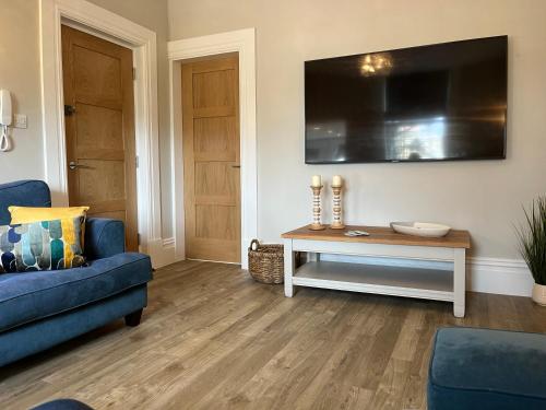 een woonkamer met een blauwe bank en een tafel bij Kings Apartment, 83 Kings Road in Harrogate