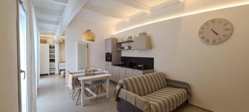 ein Wohnzimmer mit einer Uhr an der Wand und einem Tisch in der Unterkunft Appartamento Tra Cielo e Mare Cesenatico in Cesenatico