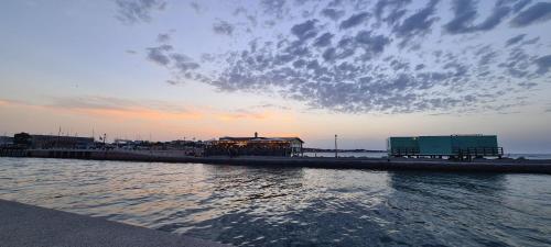 a beach with a building and the water with a cloudy sky at Appartamento Tra Cielo e Mare Cesenatico in Cesenatico