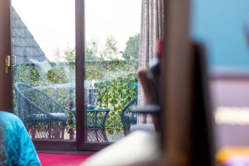a person looking out of a window at a balcony at Cricklade House Hotel, Sure Hotel Collection by Best Western in Cricklade