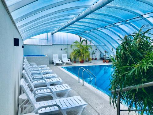 une piscine avec des chaises longues blanches et un plafond bleu dans l'établissement ENIS Hotel с минерален басейн, à Sapareva Banya
