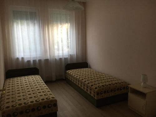 two beds in a small room with a window at Gál Vendégház 1 in Hajdúszoboszló