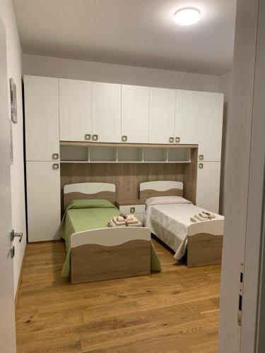 2 łóżka w pokoju z białymi szafkami i drewnianą podłogą w obiekcie La Lanterna sul mare w mieście Livorno