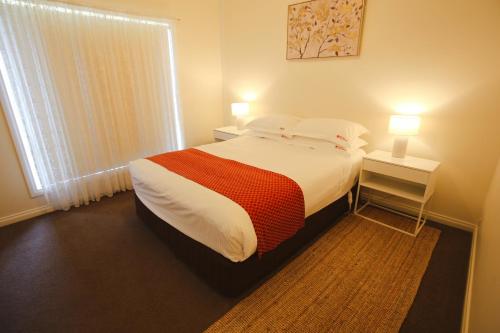 a bedroom with a bed and a window with two lamps at Wagga Showground Villas in Wagga Wagga
