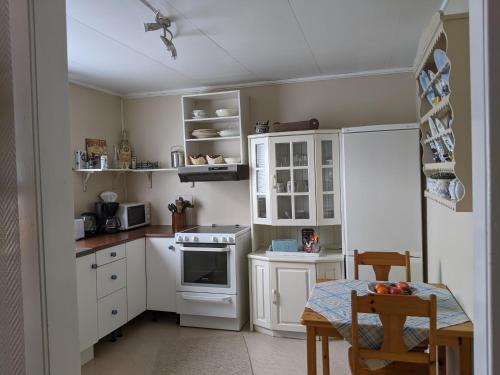 a small kitchen with white cabinets and a table at Rural apartment in Dverberg