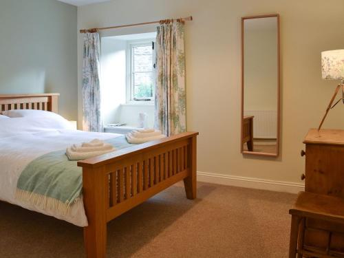 1 dormitorio con cama con espejo y ventana en Coopers Cottage, en Haverthwaite