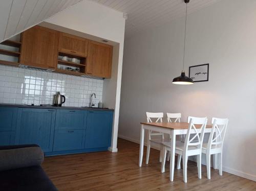 a kitchen with a table and chairs and blue cabinets at Laiko marios in Preila