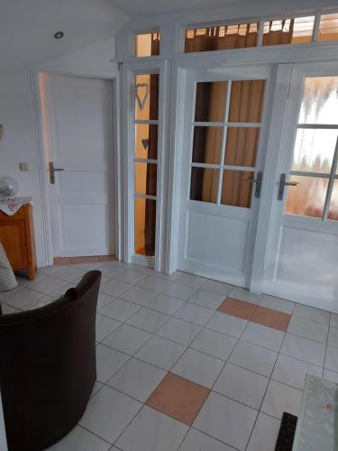 a living room with two doors and a chair at Ferienwohnung Schmitz in Anschau
