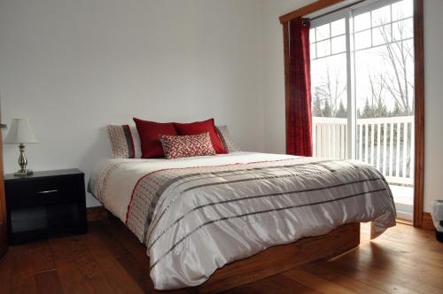 a bedroom with a bed with red pillows and a window at Chalet Rouge in New Richmond
