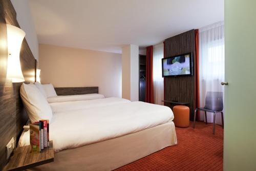 レンヌにあるイビス スタイルズ レンヌ サントル ガレ ノールの大型ベッドとテレビが備わるホテルルームです。