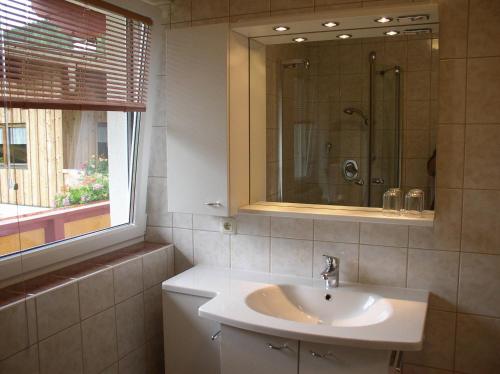 ein Bad mit einem Waschbecken, einer Dusche und einem Fenster in der Unterkunft Haus Waldfriede in Pertisau