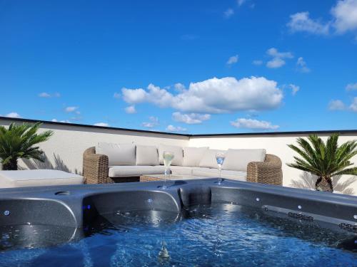 a patio with a hot tub and chairs and a tv at La Villa Thelma 5 étoiles, piscine, sauna et jacuzzi in Granville