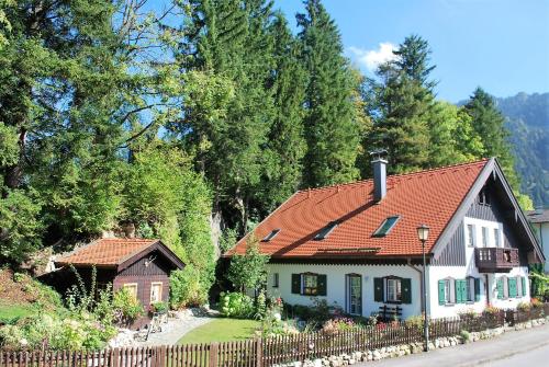 ein Haus mit rotem Dach neben einem Zaun in der Unterkunft Villa BeLucky in Oberammergau