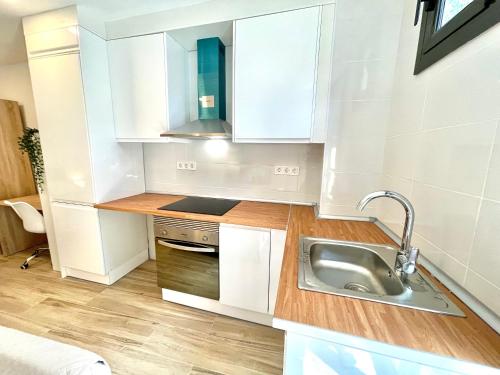 una pequeña cocina con armarios blancos y fregadero en Hospedaje24 - 3, en Manresa