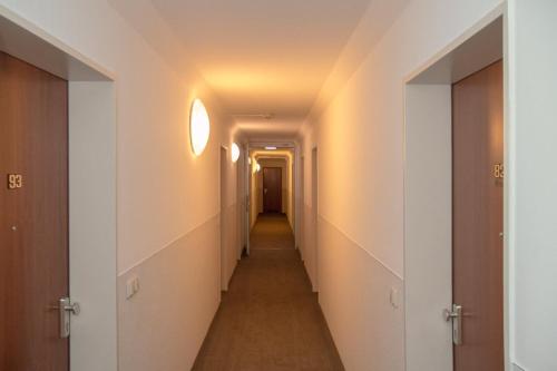 a long hallway with white walls and a ceiling at Downtown Vi Vadi Hotel in Munich