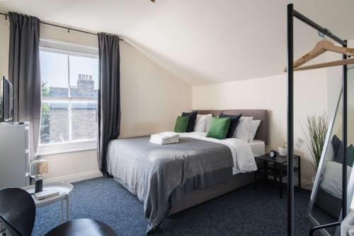 a bedroom with a bed with green pillows and a window at Two Bedroom Apartment in Tooting in London