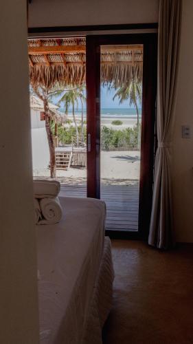 a bedroom with a view of the beach through a door at Villa Kabaceiras in Tatajuba