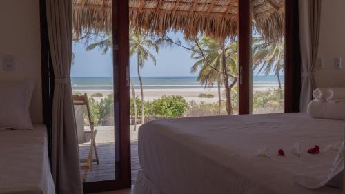 a bedroom with a bed and a view of the beach at Villa Kabaceiras in Tatajuba