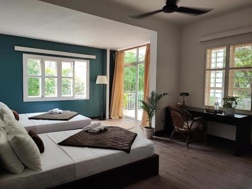 a bedroom with two beds and a desk and windows at Villa Papillon in Phnom Penh