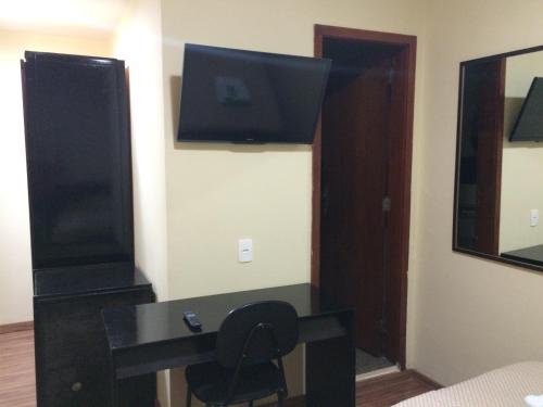 a room with a desk with a television and a chair at Hotel Americano in Rio de Janeiro