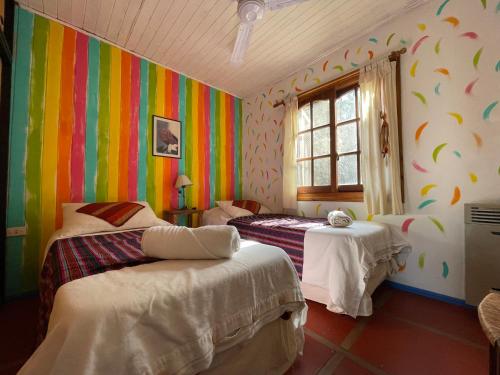 a bedroom with two beds and a colorful wall at Lipi House Hostel in Capilla del Monte