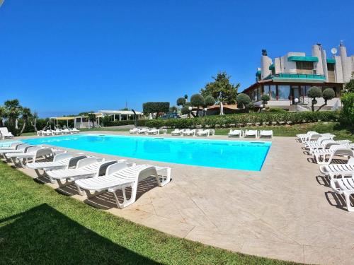 uma fila de espreguiçadeiras brancas junto a uma piscina em villalessandra em Civitavecchia