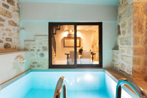 a bath tub with a mirror in a room at Ali Vafi's Villa - Heated Jacuzzi & Indoor Pool in Maroulás