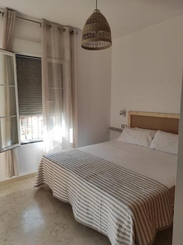 1 dormitorio con 1 cama con manta a rayas y ventana en Can Sastre Ronda, en Ronda
