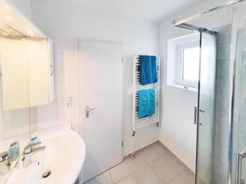a white bathroom with a sink and a shower at Ferienwohnung Gartenblick - Idylle am Travetal in Bad Oldesloe