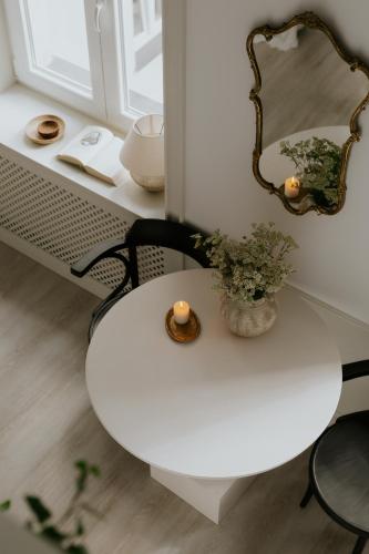 a table with a mirror and a vase with flowers on it at Lwowska Studios - STAYINWARSAW in Warsaw