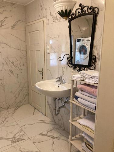 W białej łazience znajduje się umywalka i lustro. w obiekcie (C) Zimmer in einem Bauernhaus w mieście Anif