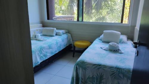 a small room with two beds and a window at Apartamento Barra Bali in Barra de São Miguel