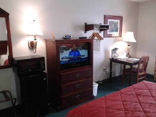 a hotel room with a television in a bedroom at Rest Inn Fort Smith in Fort Smith