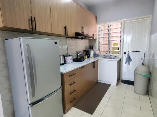 a kitchen with a white refrigerator and wooden cabinets at Doma House Alpine at Lost World of Tambun in Tambun