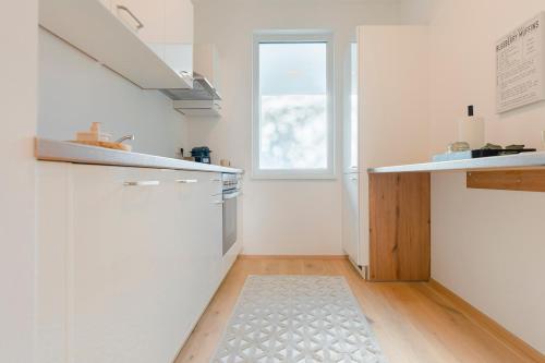 a kitchen with white walls and a wooden floor at revLIVING Garden Lounge am Steinertor Parkplatz inklusive in Krems an der Donau